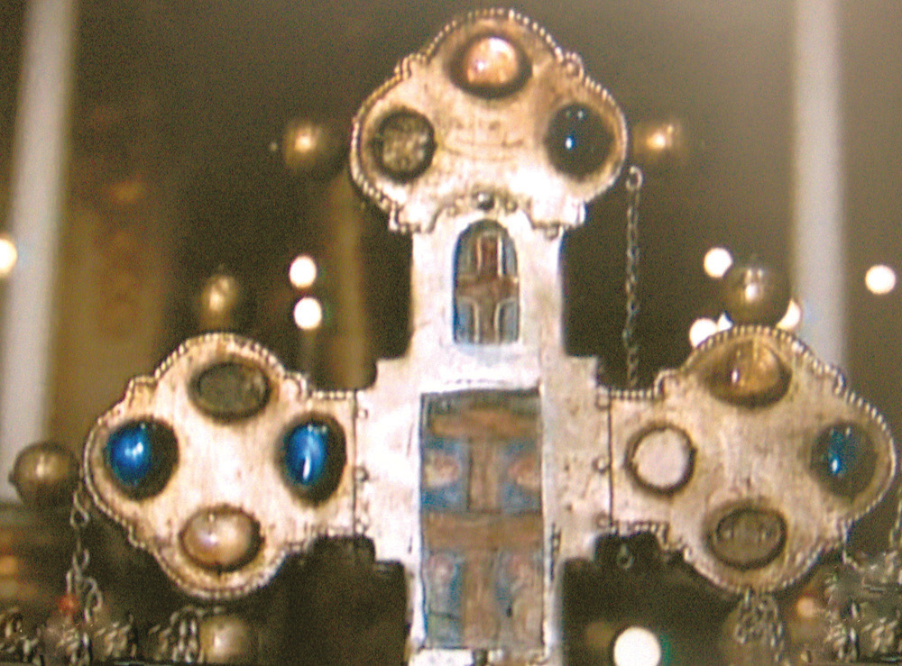Immagine ingrandita della reliquia dell'Ostia contenuta in una preziosa Croce, realizzata da un artigiano veneziano (XIII secolo) in procinto di vedere e deporre all'interno della croce. Dopo aver prestato giuramento, l'artigiano prese la pisside contenente